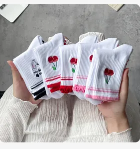 Vue détaillée de chaussettes mi-hautes blanches avec broderie de cerises et volants.