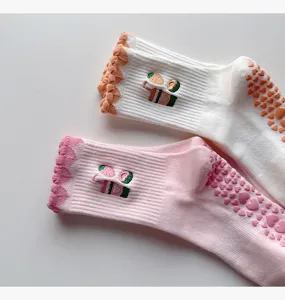 Nahaufnahme von Damen Anti-Rutsch Yogasocken mit Rüschenbündchen, Erdbeerstickerei und Herzgriffen.