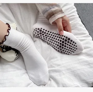 Detail view of white anti-slip yoga socks with black honeycomb silicone grips and cuffs.