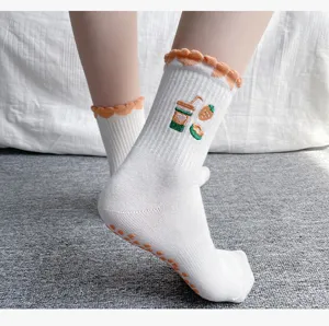 Weiße Yogasocken mit orangefarbenen Rüschenbündchen und Stickerei, rutschfeste Sohle.