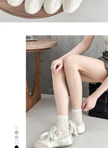 Dettaglio di calzze a tubo da donna in rete traspirante abbinate ad eleganti scarpe basse bianche.