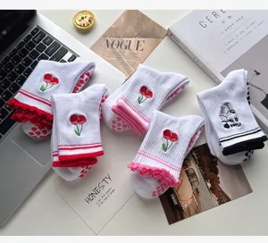 Chaussettes de yoga mi-hautes pour femmes avec broderie cerise et semelles antidérapantes.