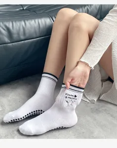Gros plan de chaussettes de yoga blanches avec broderie Pilates Martini et semelle antidérapante.