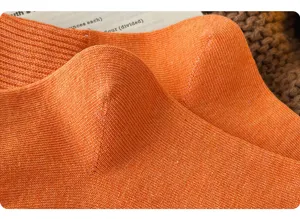 Close up of bright orange knit sock texture, showing thick cotton fabric and warm winter design.