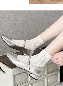 Vista dettagliata di calzini bianchi da donna in maglia traspirante abbinati a scarpe argento.
