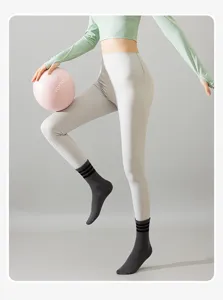 Gros plan de chaussettes de yoga mi-mollet rayées portées lors d'une séance de pilates.
