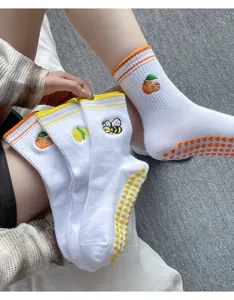 Gros plan détaillé de chaussettes de yoga blanches pour femmes avec broderie et picots.