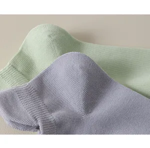 Close-up detail shot of pure cotton women's ribbed short socks in pastel green and purple.