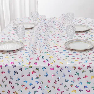 Detailed close-up view of colorful butterfly print tablecloth on a nicely set dining table.