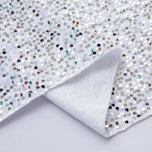 Primo piano dettagliato di tessuto bianco con paillettes scintillanti per decorazioni.