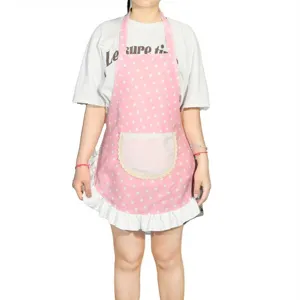 Detailed view of a cute pink polka dot kitchen apron featuring a white ruffle hem and pocket.