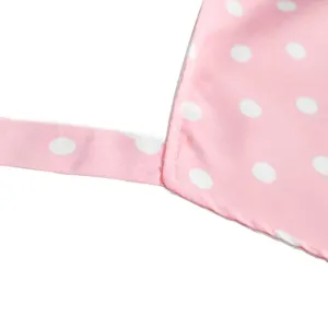 Pink polka dot apron fabric detail close up showing white dots and neat stitched strap edge.
