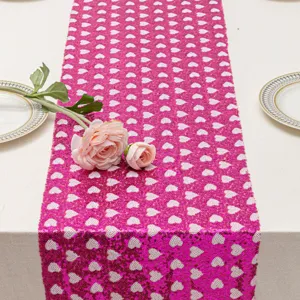 Camino de mesa de lentejuelas rosas con patrón de corazones blancos para fiesta.