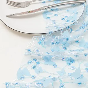 Dettaglio runner da tavola farfalla 3D blu in tessuto mesh delicato con paillettes brillanti.