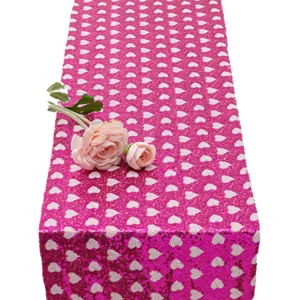 Camino de mesa de lentejuelas rosas con corazones blancos para fiestas y bodas.