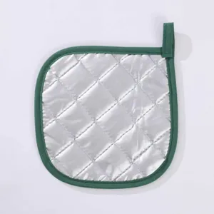 Silver coated heat resistant kitchen pad detail view with green edge and hanging loop.