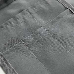 Primo piano dettaglio della tasca del grembiule da lavoro grigio con cuciture resistenti.