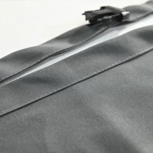 Dettaglio del grembiule da lavoro grigio con tessuto resistente, cuciture e fibbia.