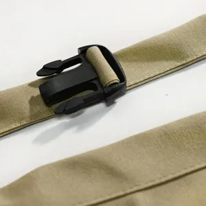 Primo piano del cinturino del grembiule kaki e della fibbia in plastica nera, accessorio robusto.