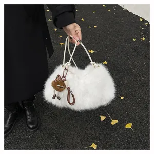 Detail einer weißen flauschigen Kunstpelz-Achseltasche mit Taschenanhänger im Herbst