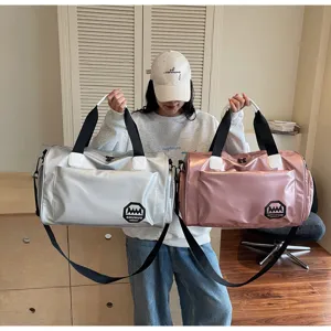 Model holding silver and pink waterproof duffel bags showing large capacity for travel.