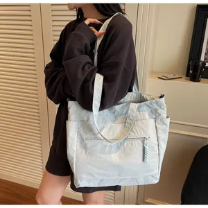 Dettaglio ravvicinato di una grande borsa tote in tela celeste con pratiche tasche laterali