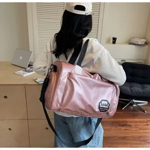 Pink metallic waterproof travel duffel bag carried by a model in a casual setting