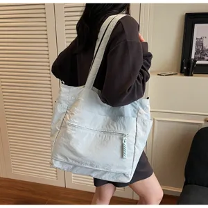 Grande borsa tote in nylon azzurro indossata da una modella in un ambiente interno