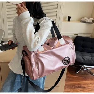 Close-up of a stylish pink shiny waterproof duffle bag held by a model
