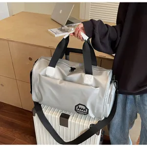 Silver waterproof large capacity duffle bag with trolley sleeve resting on white suitcase