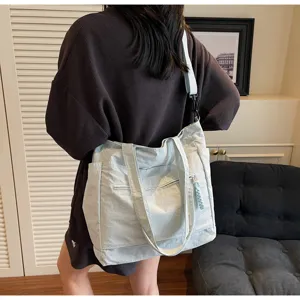 Ampia borsa tote in tela azzurro chiaro indossata da una donna per scuola e pendolarismo