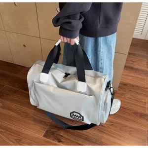 Person holding a large grey waterproof travel duffel bag in a modern indoor setting
