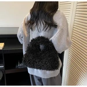 Detailansicht einer schwarzen flauschigen Kunstpelz-Kettentasche auf einem grauen Pullover