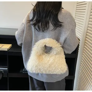 Weiße flauschige Kunstpelz-Eimertasche mit Kettenriemen über einem grauen Pullover