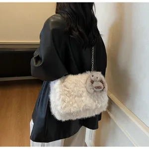 Detail einer weißen Plüsch-Umhängetasche mit Kettenriemen und Hasenanhänger-Accessoire