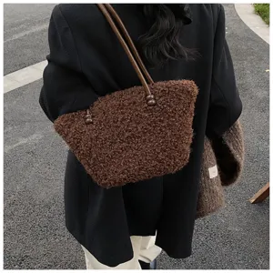 Detail view of fuzzy brown faux lamb wool tote bag worn by a model in a street style setting