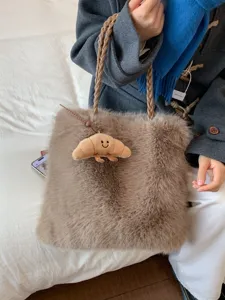 Große braune flauschige Tragetasche mit geflochtenen Griffen und Croissant-Anhänger.