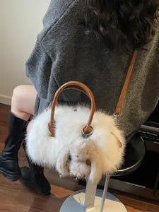 Elegant white faux fur Boston handbag with brown handles and a cute rabbit charm