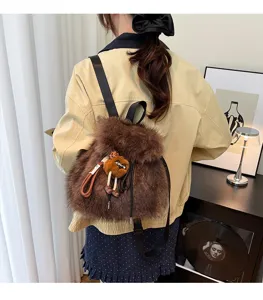 Rückansicht eines Models mit flauschigem braunem Kunstpelz-Rucksack und Anhänger