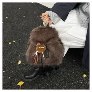 Detailaufnahme eines flauschigen braunen Kunstpelzrucksacks mit süßem Plüschtieranhänger.