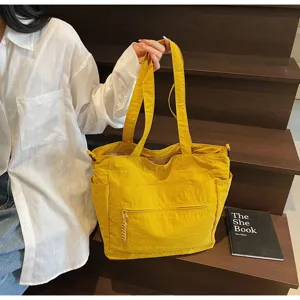 Dettaglio di una grande borsa tote in tela gialla tenuta da una modella per pendolari