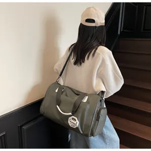Model carrying a green large-capacity waterproof travel duffel bag on a staircase