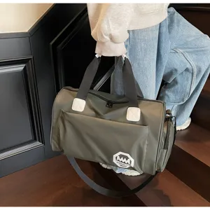 Detail view of large olive green waterproof travel duffel bag carried on a staircase