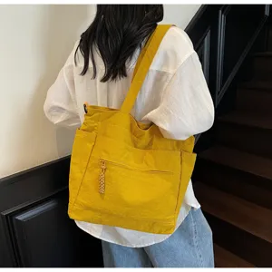 Grande borsa tote in tela gialla indossata dal modello per il pendolarismo e la scuola.