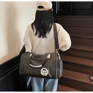 Close-up of a large grey waterproof travel duffel bag carried by a model on stairs