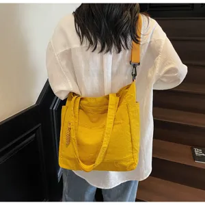 Vista dettagliata di una grande borsa tote in tela gialla con tracolla regolabile su modella.