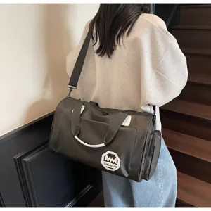 Close-up detail of a large capacity dark gray travel duffel bag carried by a model.