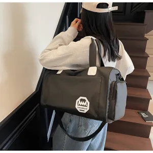 Rear view of a model carrying a black waterproof large capacity travel and gym duffel bag