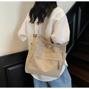 Grande borsa tote in tela beige vista da dietro su una modella, ideale per il pendolarismo.