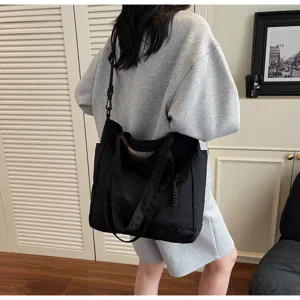 Grande borsa tote in tela nera indossata da una modella, ideale per il lavoro o la scuola